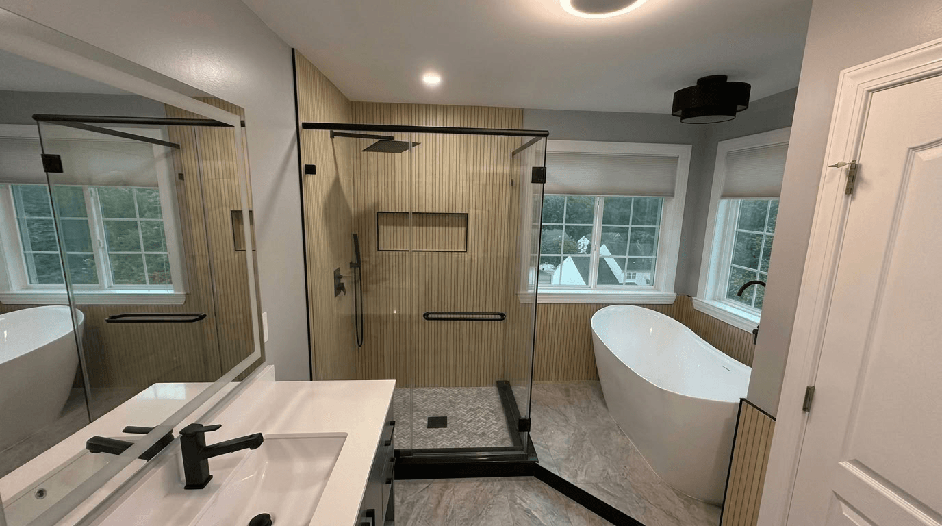 Modern bathroom with a glass walk-in shower, freestanding white bathtub by windows, and vanity with black fixtures