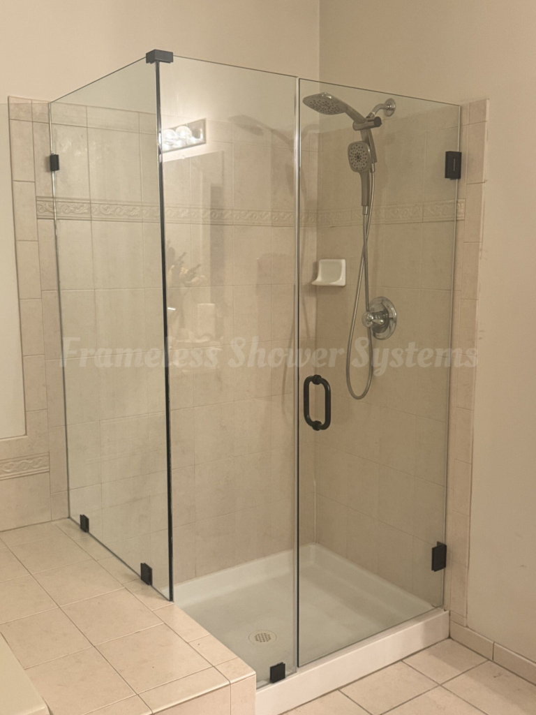 Frameless glass shower enclosure with matte black hardware, hinged glass door, and beige tiled walls