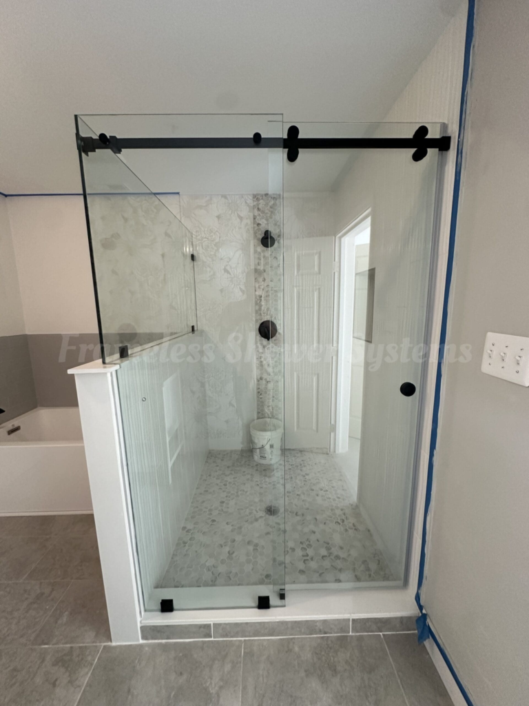 Modern walk-in shower featuring a frameless sliding glass door with matte black hardware and tiled interior