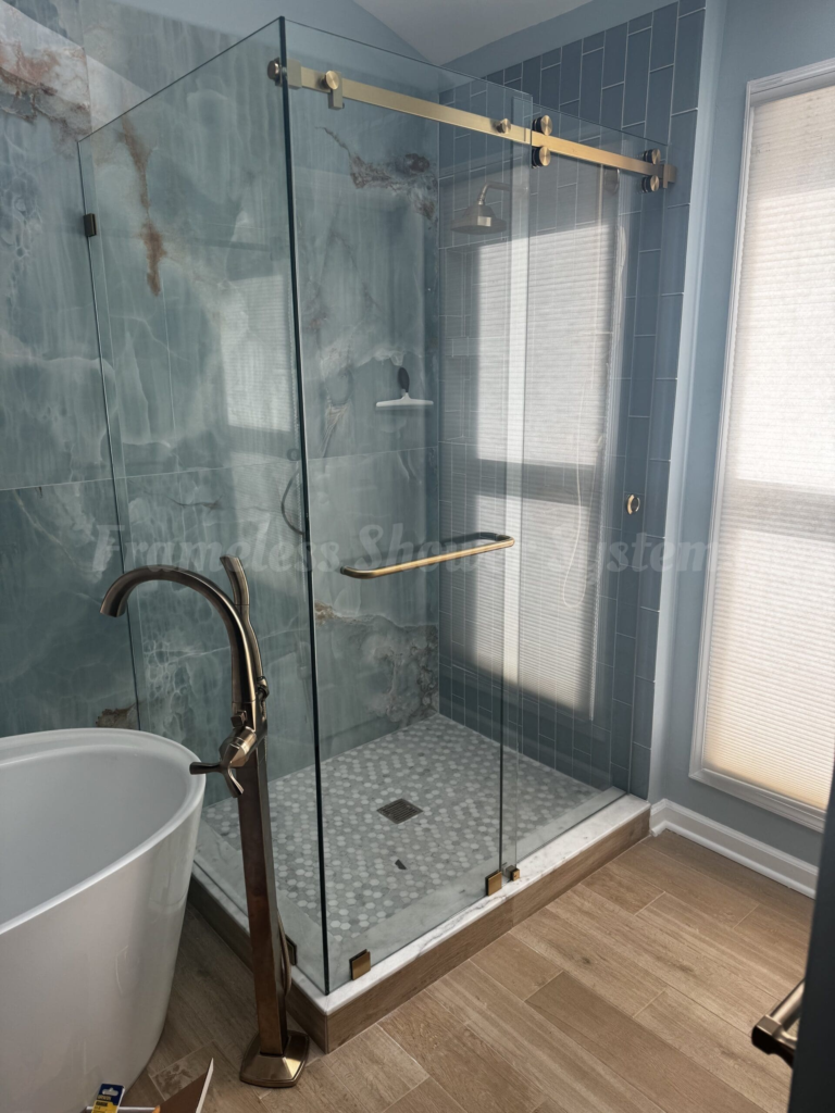 Frameless sliding glass shower enclosure with brushed brass hardware and blue marble tile