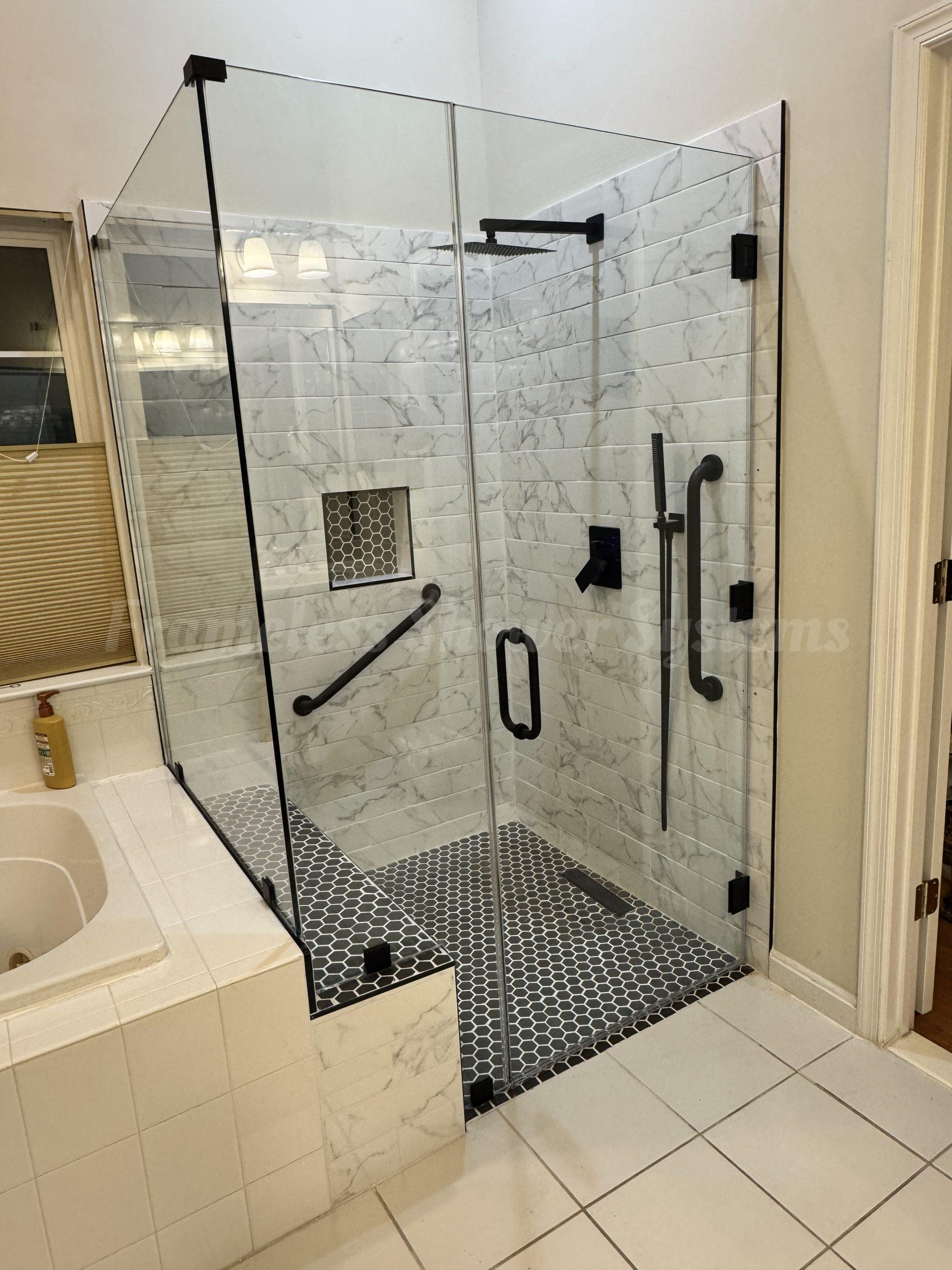 Modern glass walk-in shower featuring white marble wall tile, dark hexagon floor tile, matte black fixtures, and grab bars