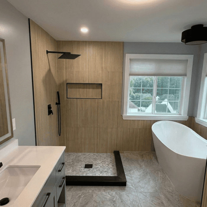 Modern bathroom with a white vanity, freestanding soaking tub, walk-in shower with wood-slat tile, and matte black fixtures