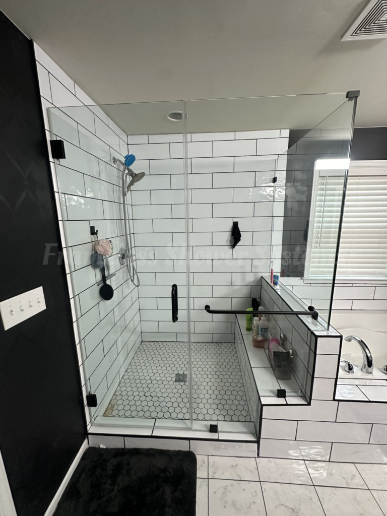 Frameless glass walk-in shower featuring white subway tile, black hardware, and hexagon floor tile