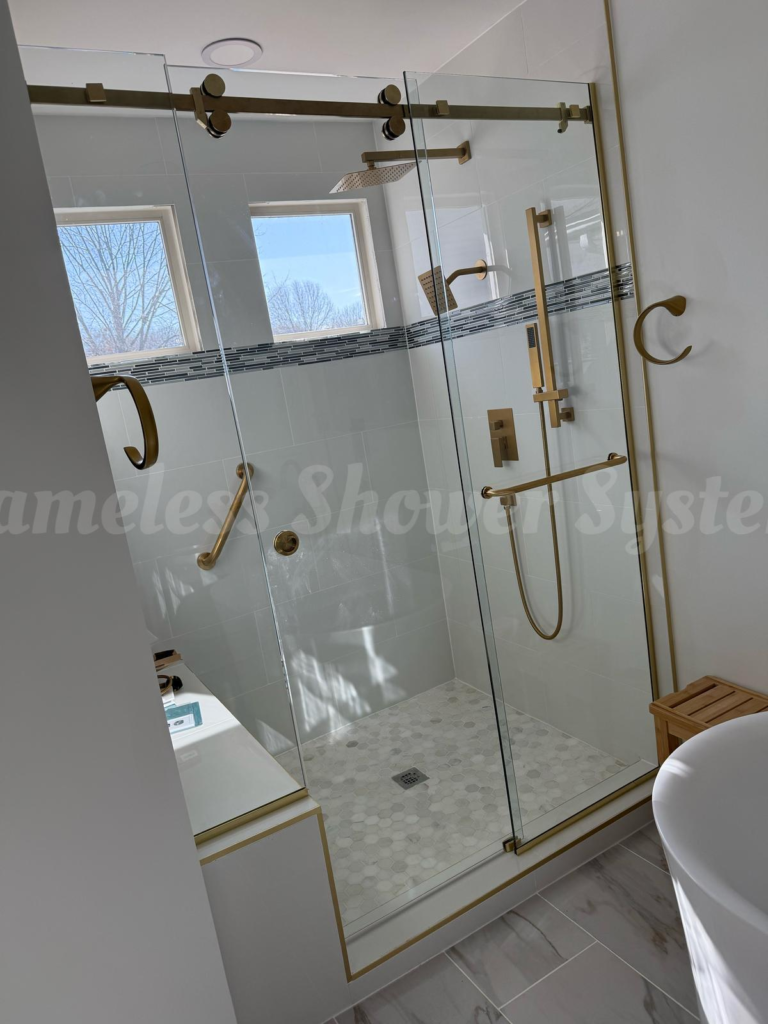 Modern walk-in glass shower featuring brushed gold fixtures, dual shower heads, grab bars, and white tiled walls