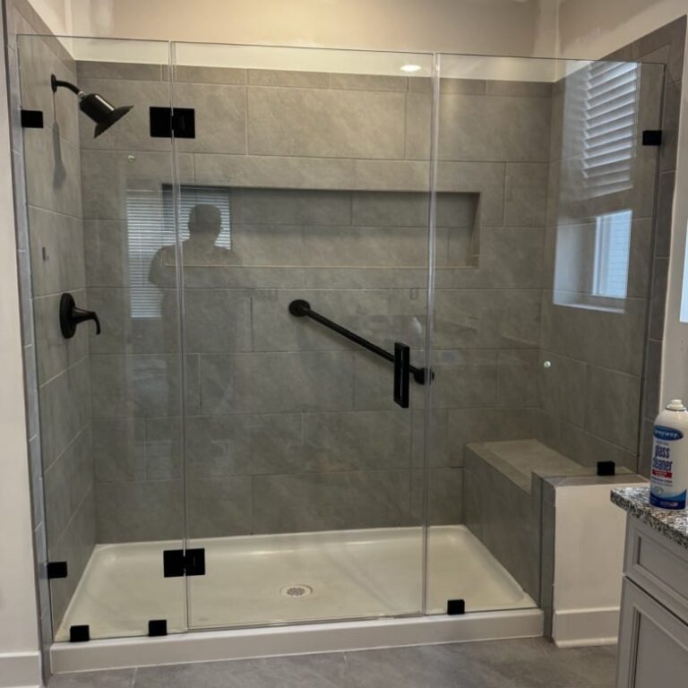Frameless glass shower enclosure with black hardware and gray tile walls
